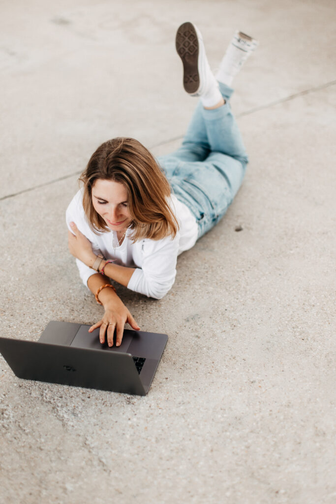 Frau liegt mit Laptop auf dem Boden. Modernes Brandingfoto einer jungen Frau