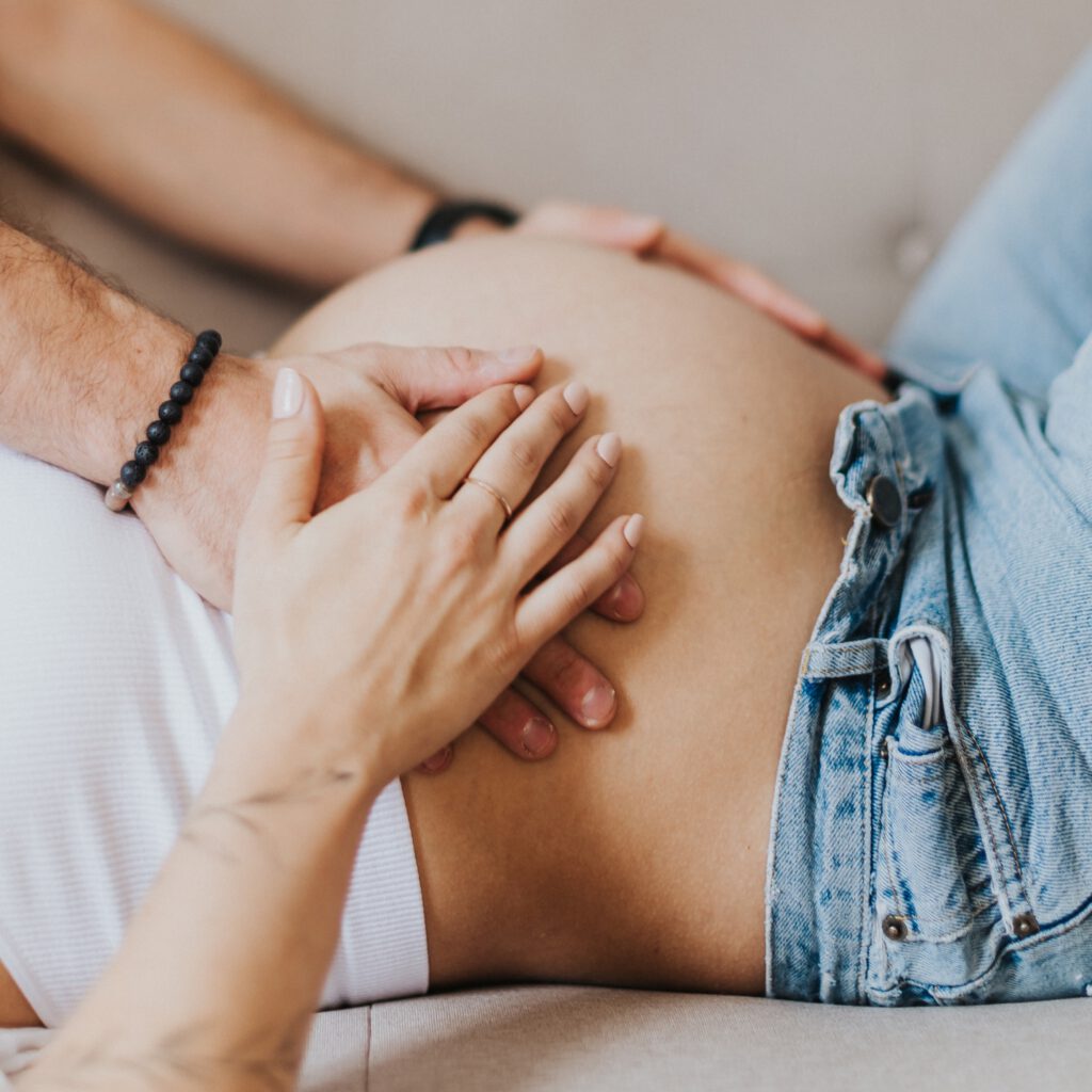 Detailaufnahme von einem Babybauch mit den Händen der Frau und des Partners