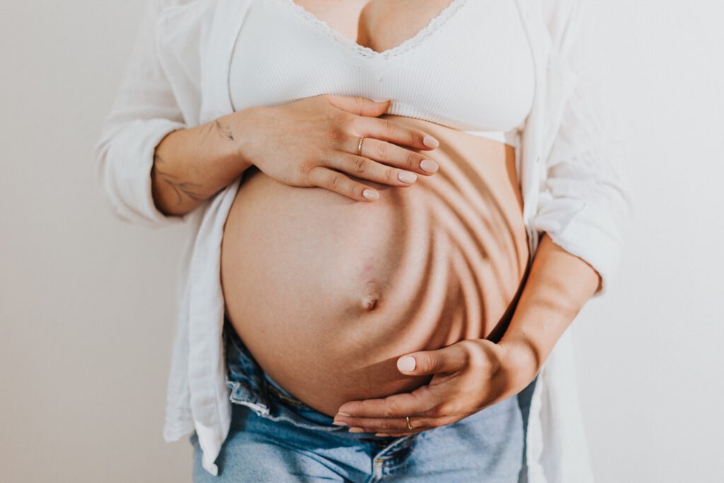 Detailaufnahme eines Babybauches mit einem Palmwedelschatten auf dem Bauch