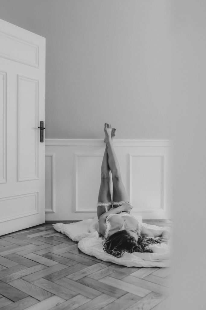 Boudoirfoto liegend mit Füßen an einer weißen Stuckwand. Edel und besonders